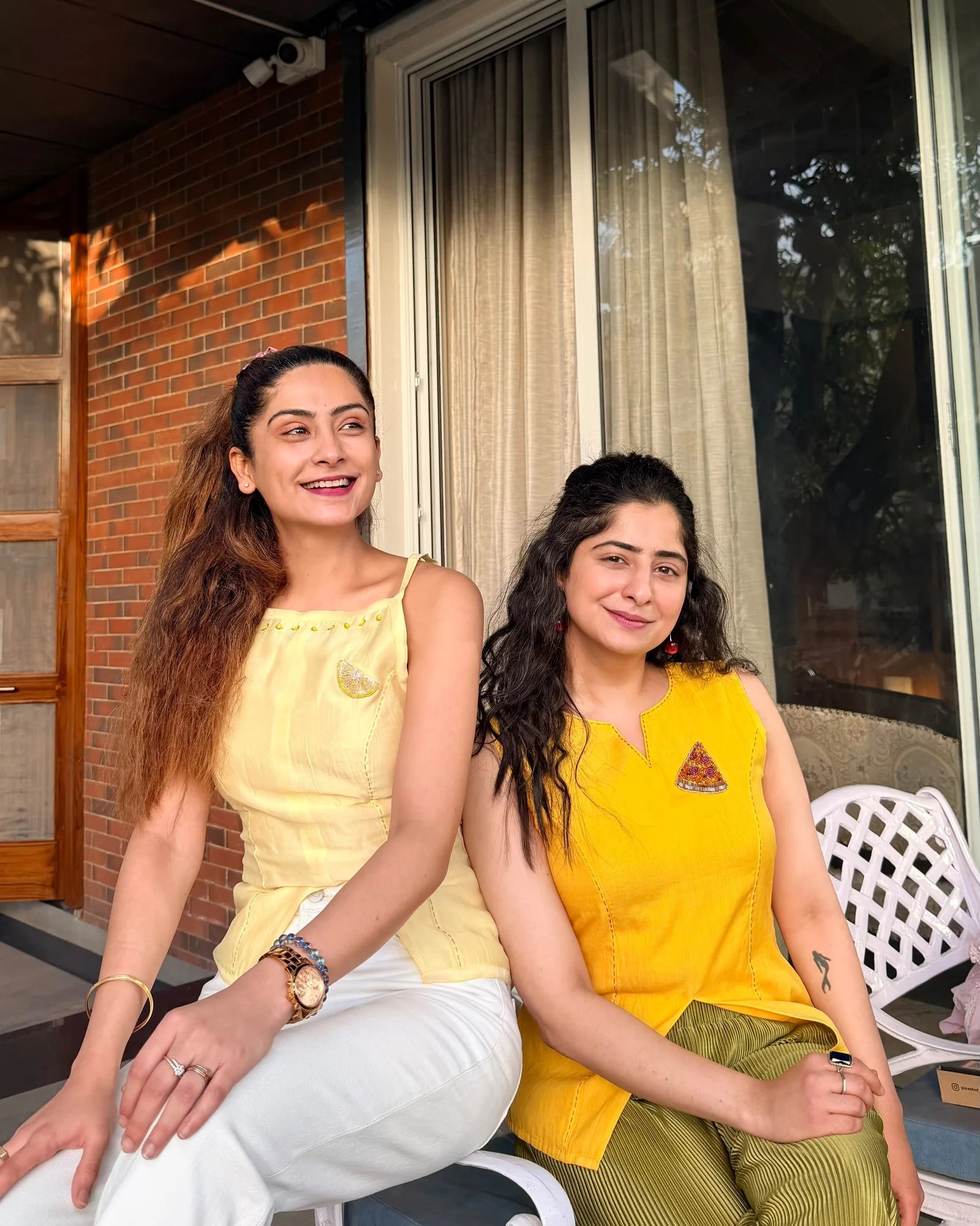 Two women wearing custom Designer for a Day tops with hand-embroidered brooches